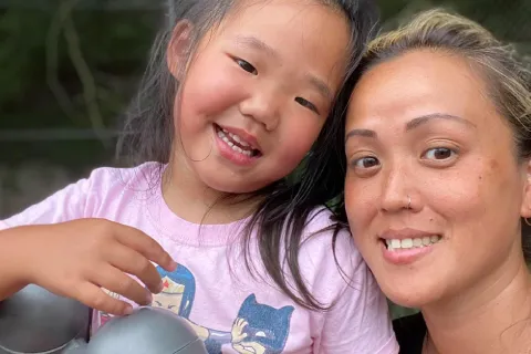 Little girl with woman looking at camera